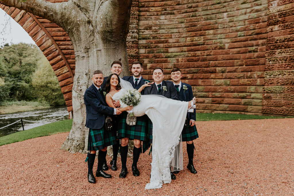 Bride posing with groomsmen at brig o doon